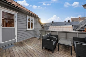 A covered outdoor patio with wicker furniture and a view of neighboring buildings. - Roof Terrace 3BR - Unesco Bryggen and Floien (Bergen)