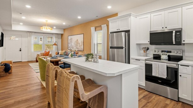 A modern kitchen with white cabinetry, stainless steel appliances, and a central island.