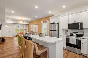A modern kitchen with white cabinetry, stainless steel appliances, and a central island.