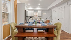 A dining area with a wooden table, chairs, and a kitchen in the background.