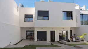 Un edifici modern de dos pisos amb teulada plana, finestres grans i una petita zona d'estar a l'exterior.