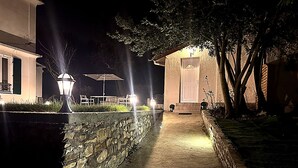 A nighttime pathway leading to a building with outdoor seating and a stone wall. - New cosy home & private garden -Near Paris - Free parking (Franconville)