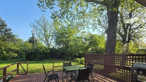 Une terrasse en bois avec une table et des chaises, entourée d’une clôture en bois et d’arbres.