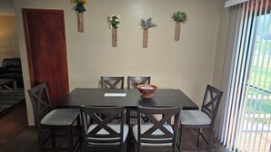 Un espace repas comprenant une table, des chaises, une porte en bois et des jardinières fixées au mur.
