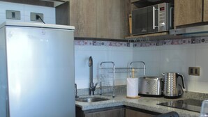 A kitchen with a refrigerator, microwave, toaster, kettle, and a sink with a faucet. - Disegni 19 - Dpto. Downtown Copiapó City View (Copiapó)