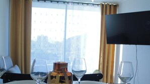 A hotel room with a dining table, four wine glasses, a bottle, and a TV mounted on the wall. - Disegni 19 - Dpto. Downtown Copiapó City View (Copiapó)