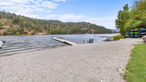 Une jetée en gravier qui s’avance dans un lac, entourée d’arbres et d’une petite cabane.