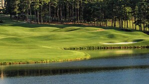 A golf course with water hazards, sand bunkers, and a building in the background.