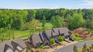 A residential area with houses, a golf course, and a forested background.