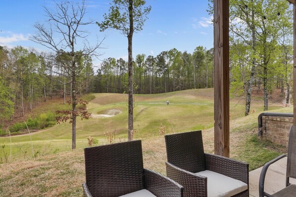 A covered outdoor seating area with wicker furniture overlooking a golf course. - RTJ Golf Retreat | Fairway Views · Sleeps 8 (Bessemer)