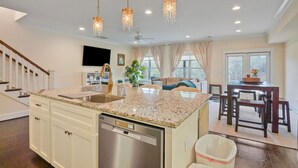 A modern kitchen with granite countertops, a dishwasher, and a dining area with a wooden table and chairs.