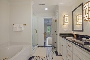 A modern bathroom with a bathtub, a glass-enclosed shower, a vanity with a sink, and a large mirror. - RTJ Golf Retreat | Fairway Views · Sleeps 8 (Bessemer)