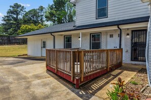 Ein zweistöckiges Haus mit Veranda, Garage und einem eingezäunten Garten.