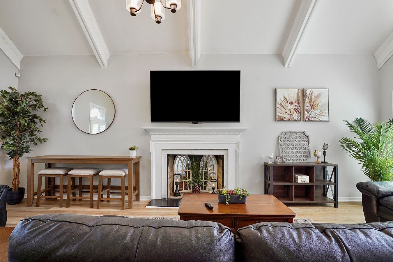 A living room with a fireplace, a television, a dining area, and a large plant.