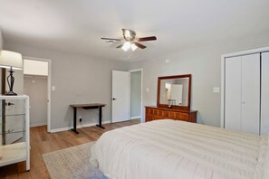 Une chambre à coucher comprenant un lit, une commode, un bureau et un ventilateur de plafond.