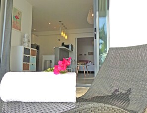 Ein modernes Wohnzimmer mit Sofa, einem Essbereich und einer Küche im Hintergrund.