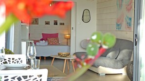 En modern inredning med en säng, en soffa, ett matbord med stolar och ett litet bord med en skål och ett glas.