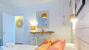A bedroom with a bed, a bedside table, a mirror, and a hanging light fixture.