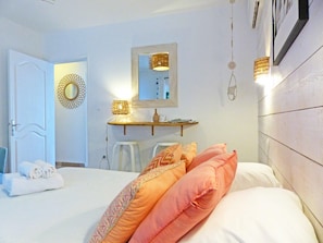 A bedroom with a bed, a bedside table, a mirror, and a hanging light fixture. - Appartement Le Bel avec terrasse, incredible sea view and pool space (Petite Île)