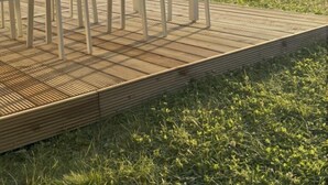 Um pátio com móveis de exterior e vista para um campo gramado e árvores.