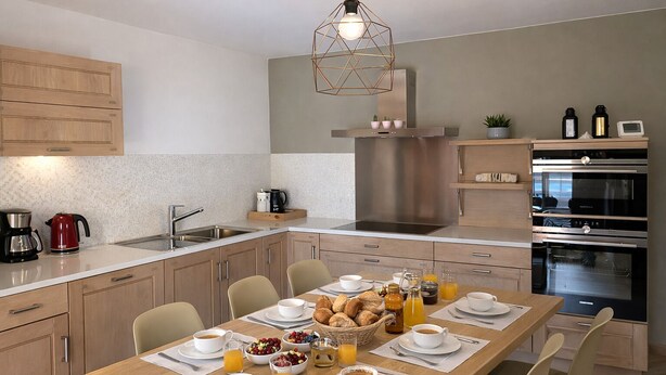 Cozinha moderna com área de refeições, eletrodomésticos de aço inoxidável e espaço para café da manhã.