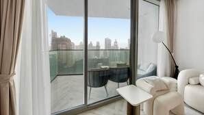 A modern living room with a large sliding glass door, a sofa, a small table, and a floor lamp. - Luxury 1BR l Burj Khalifa View in Business Bay (Dubai)
