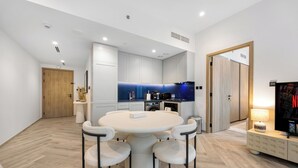 A modern kitchen with white cabinets, a blue backsplash, and a dining area with a round table and chairs. - Luxury 1BR l Burj Khalifa View in Business Bay (Dubai)