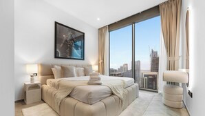 A modern bedroom with a large bed, a city view, and a framed artwork on the wall. - Luxury 1BR l Burj Khalifa View in Business Bay (Dubai)