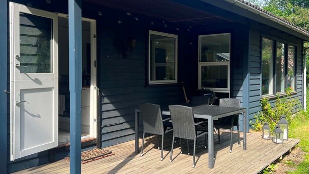 Un espacio al aire libre cubierto con una mesa, sillas, una puerta y una ventana.