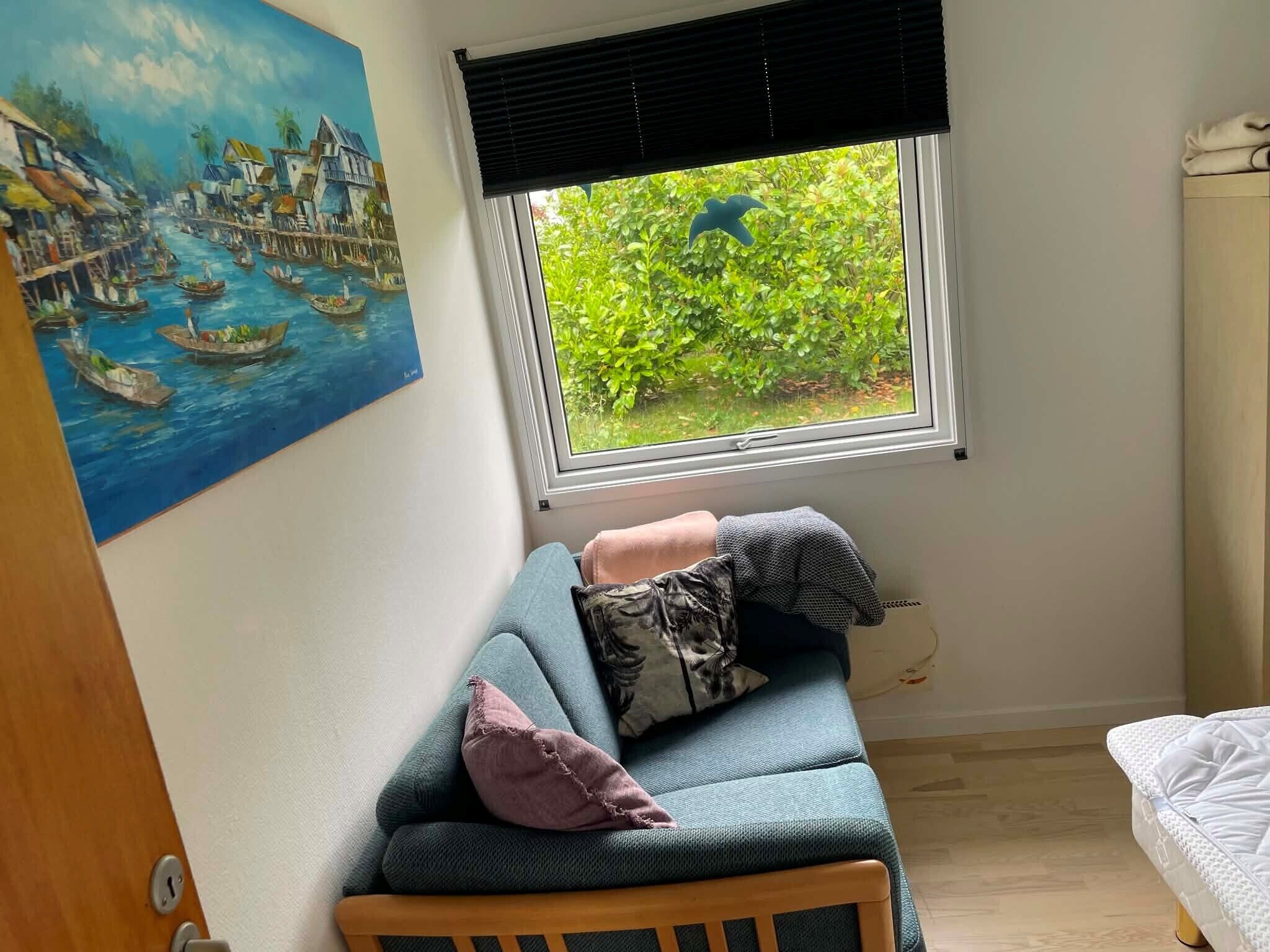 A room with a window, a painting, a sofa, and a bed.