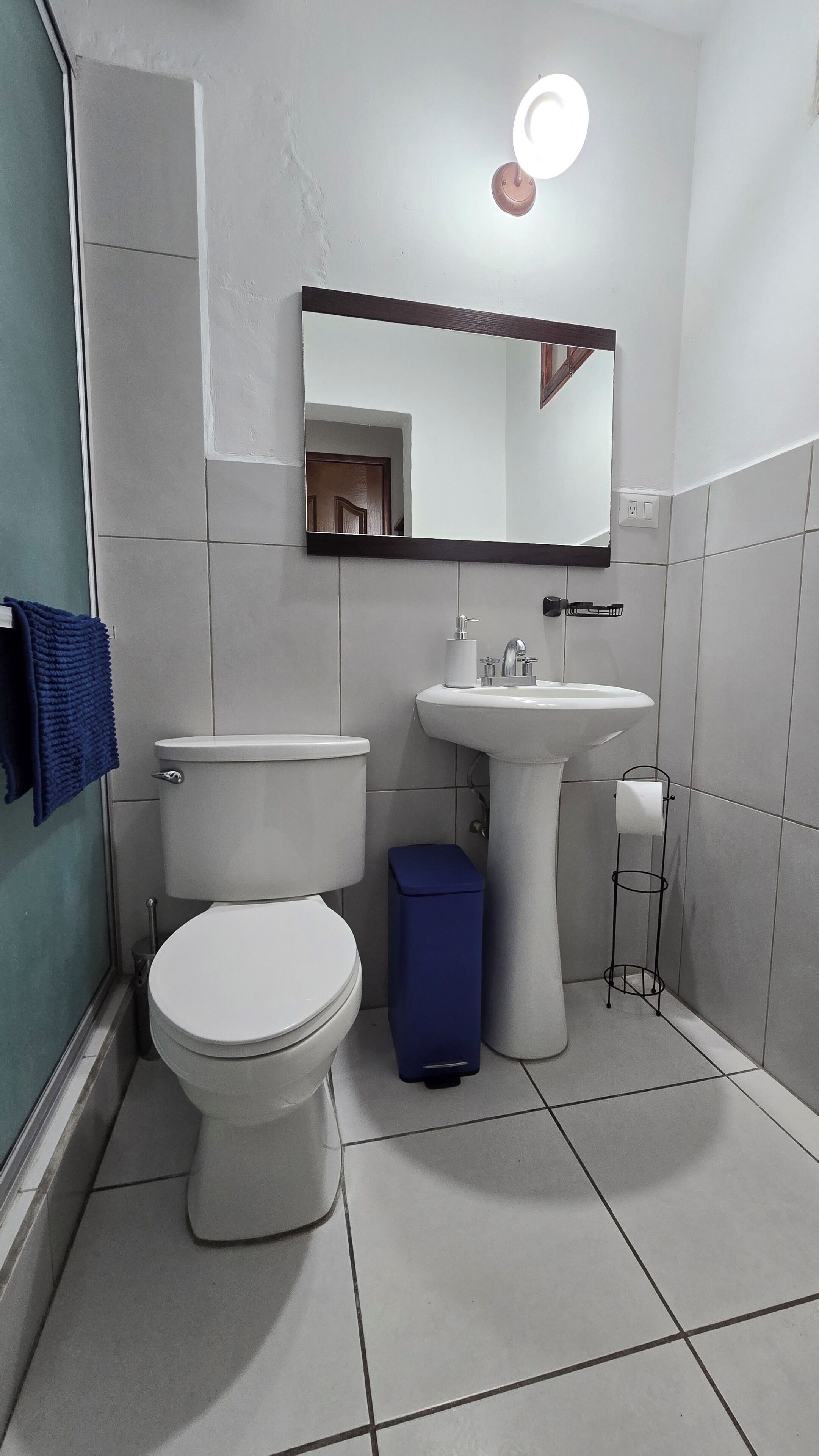 A bathroom with a toilet, sink, and mirror.