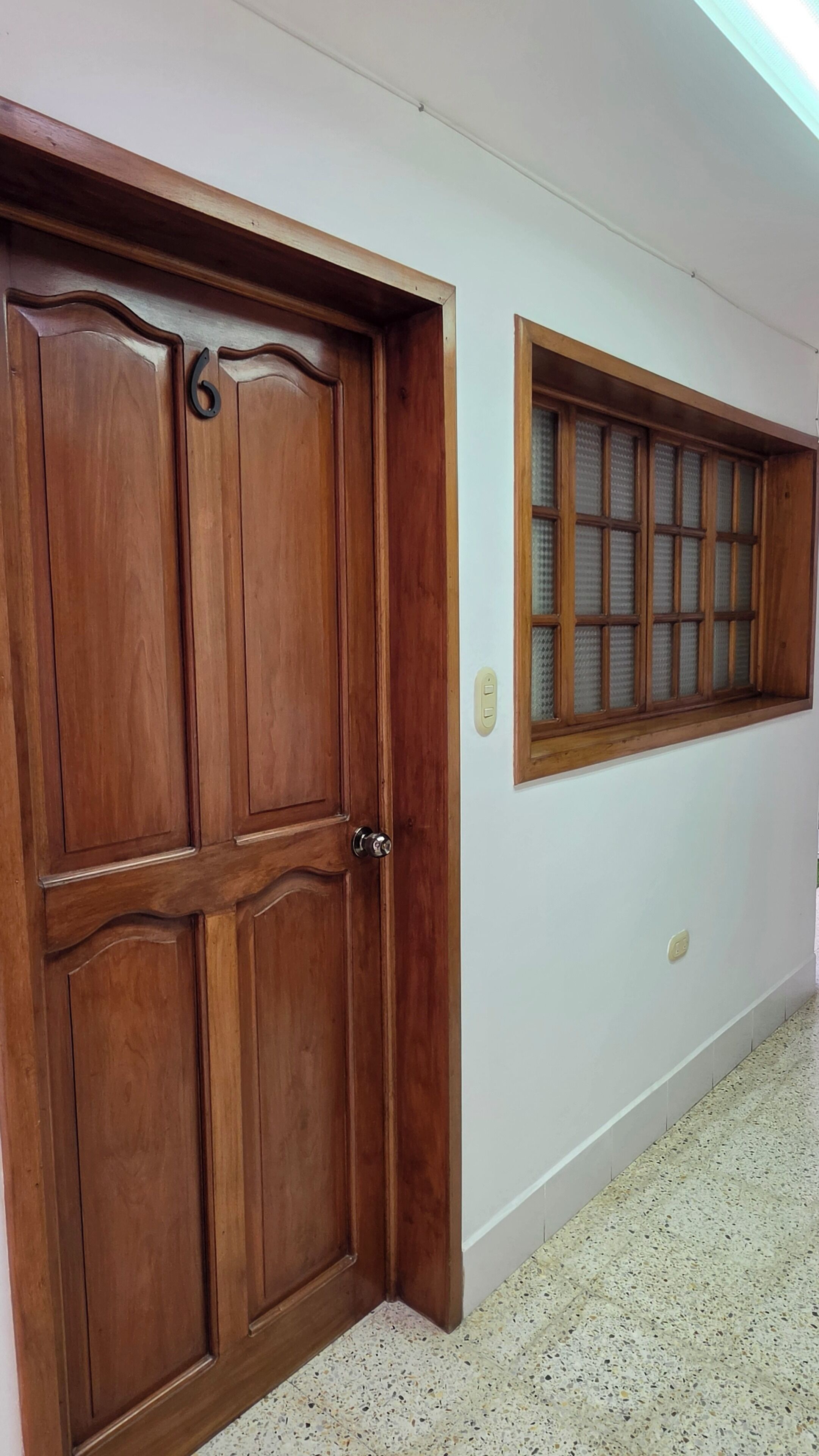 A hallway with a wooden door and a window with frosted glass.