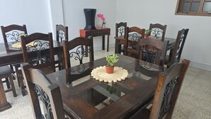 Een eettafel met een glazen blad, omringd door houten stoelen met metalen poten.