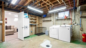 A laundry room with a washing machine, dryer, and a metal cage. - 5BR 2BA - Northglenn Bungalow, Family-Friendly Stay Near Denver & Boulder (Northglenn)