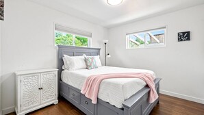 A bedroom with a bed, a nightstand, a dresser, two windows, and a ceiling light. - 5BR 2BA - Northglenn Bungalow, Family-Friendly Stay Near Denver & Boulder (Northglenn)