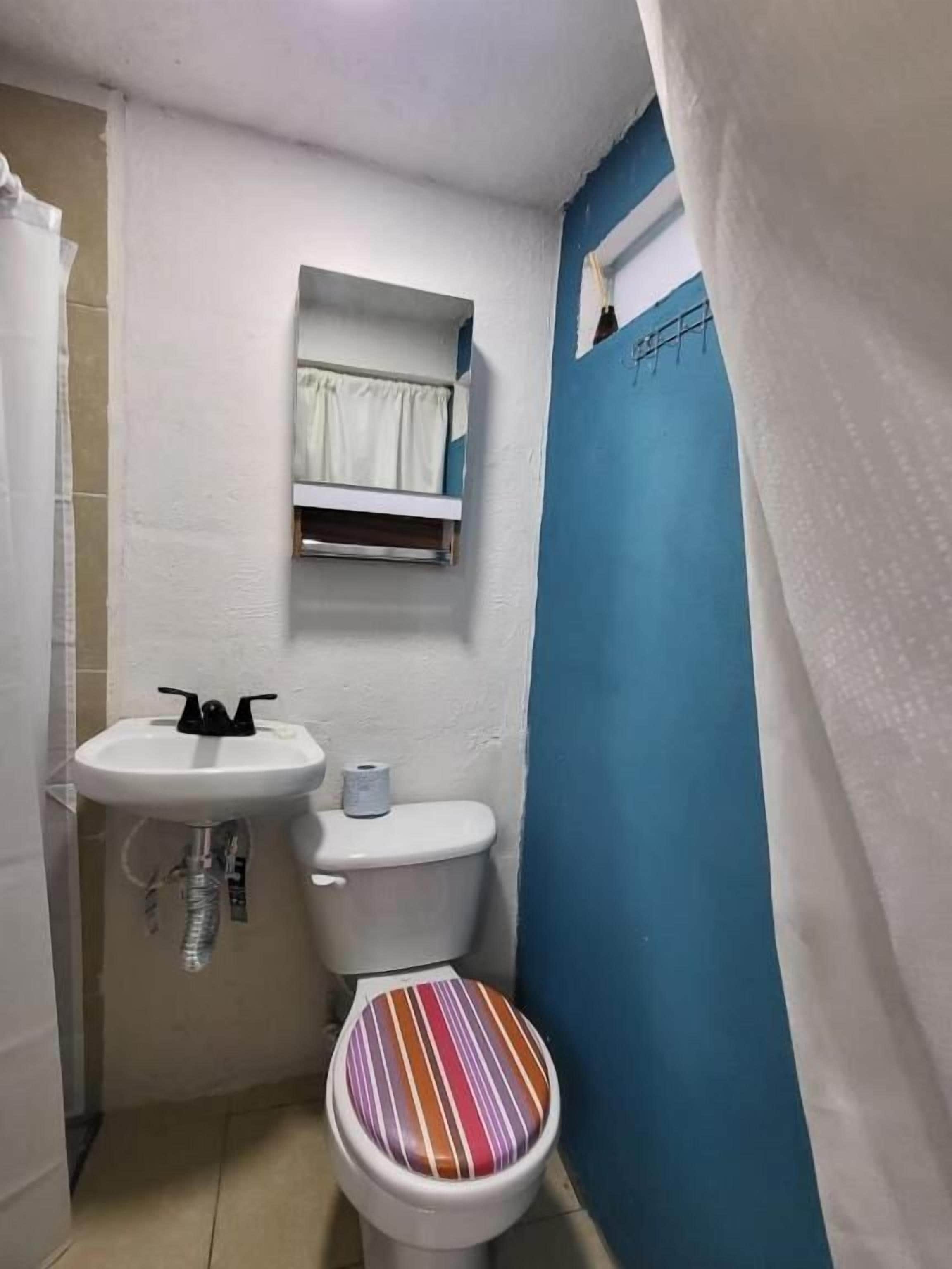 Een kleine badkamer met een wit wastafel, toilet en een blauwe wand.