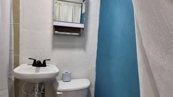 Een kleine badkamer met een wit wastafel, toilet en een blauwe wand.