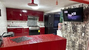A kitchen with red cabinets, a central island, a stove, and a refrigerator. - Hospedaje Casa Vazquez  (Pachuca)