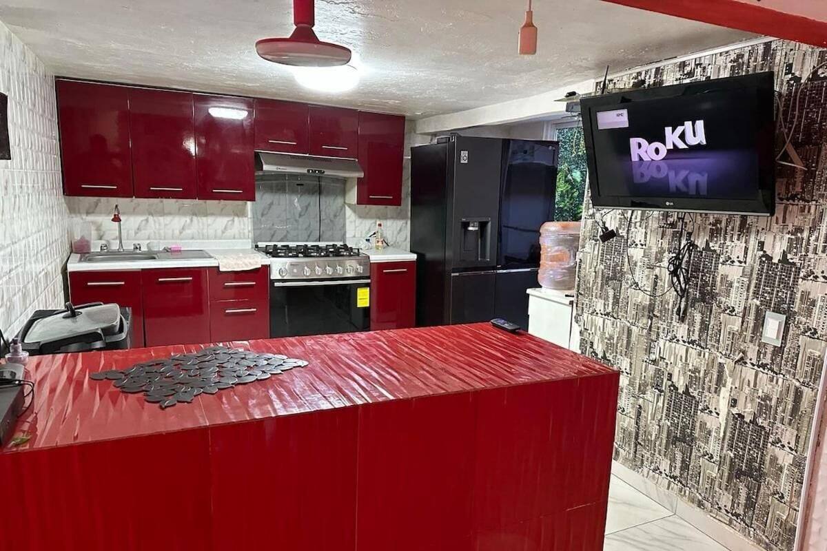 A kitchen with red cabinets, a central island, a stove, and a refrigerator.