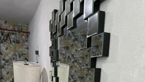 A room with a wall-mounted mirror, a bedside lamp, a bed with patterned bedding, and a wooden floor. - Hospedaje Casa Vazquez  (Pachuca)