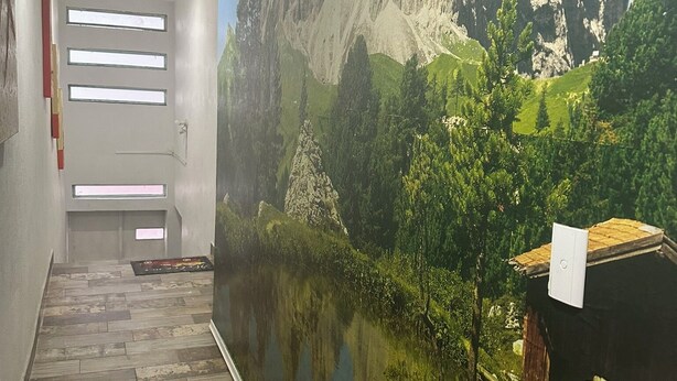 A hallway with a mural of a mountainous landscape, a wooden floor, and a door with windows. - Hospedaje Casa Vazquez  (Pachuca)