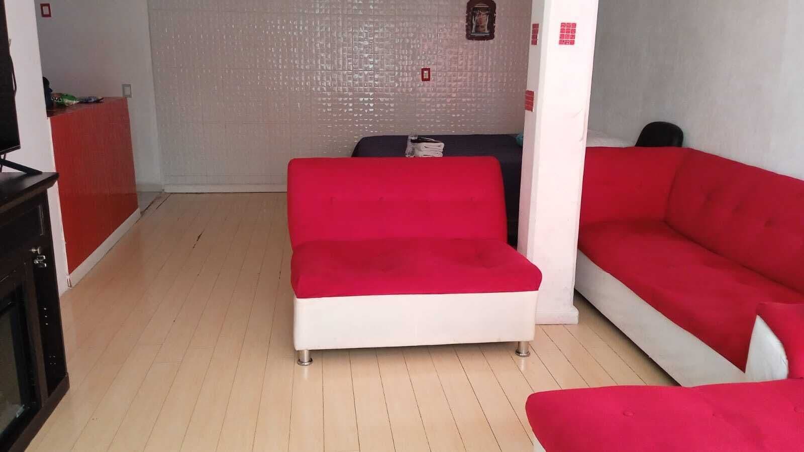 A room with a red sofa, a white sofa, and a black cabinet.