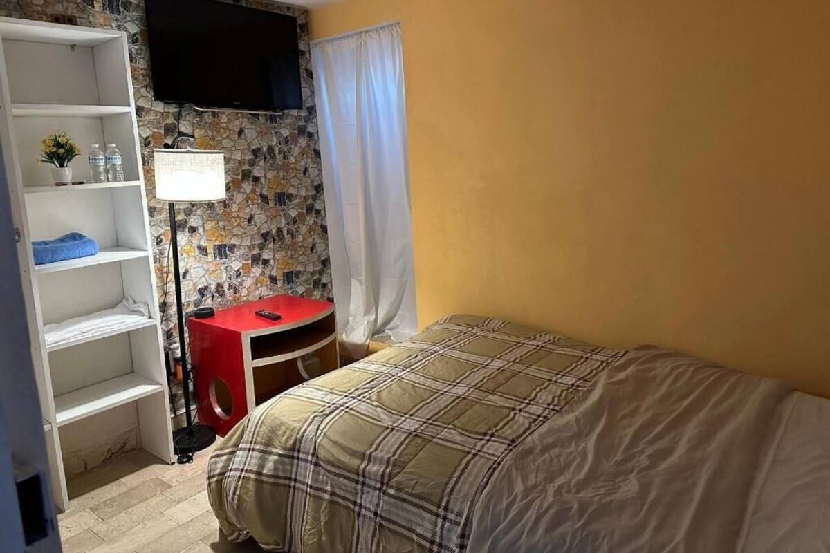 A bedroom with a bed, a desk, a TV, and a wardrobe.
