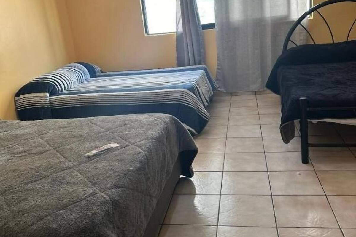 A room with two beds, a window with curtains, and a metal bed frame.