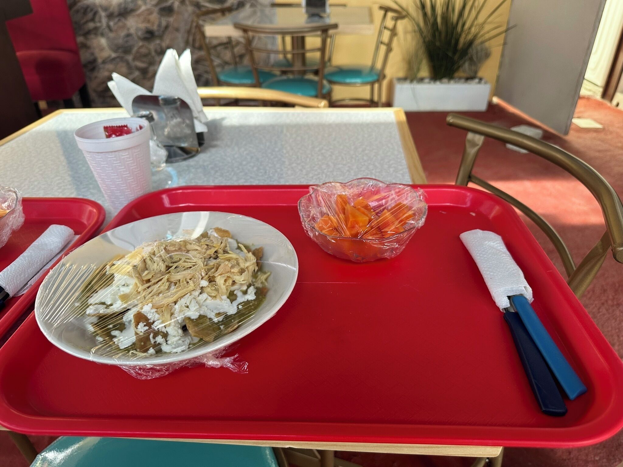 A tray with a plate of food, a bowl of vegetables, and utensils on a table.