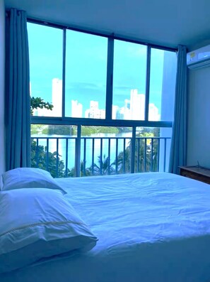 A hotel room with a large window, a bed, and a view of a city skyline. - CARTAGENA-Vista al Laguito 🌅 | Remodeled | VRBO Ready | Steps from the beach. (Cartagena de Indias)