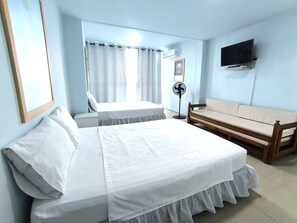A hotel room with a bed, a sofa, a TV, and a fan. - CARTAGENA-Vista al Laguito 🌅 | Remodeled | VRBO Ready | Steps from the beach. (Cartagena de Indias)