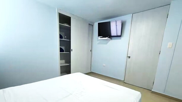 A bedroom with a bed, a wardrobe, and a television mounted on the wall. - CARTAGENA-Vista al Laguito 🌅 | Remodeled | VRBO Ready | Steps from the beach. (Cartagena de Indias)
