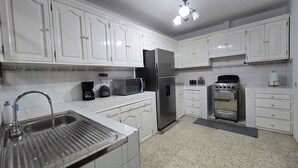 Cucina con pensili bianchi, frigorifero in acciaio inossidabile, microonde, piano cottura e lavello.