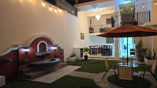 Un cortile con una fontana, posti a sedere all'aperto e luci decorative.